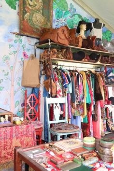 a room filled with lots of different types of clothing and accessories on shelves next to a table