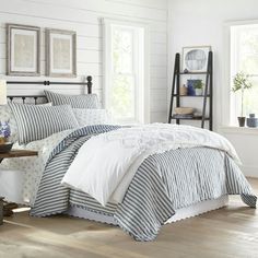 a bed with white and blue striped comforter in a bedroom next to a window