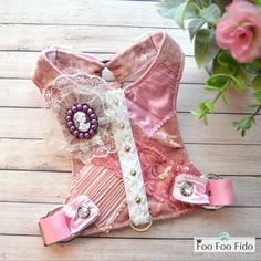 a pink boot with lace and pearls on the side sitting on a wooden floor next to flowers