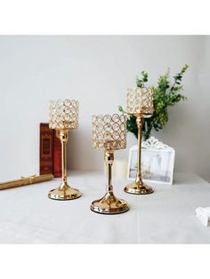 three gold candlesticks on a white table