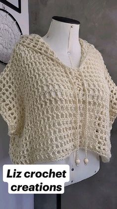 a white crochet shawl on a mannequin with the words liz crochet creations below it