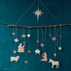 christmas decorations hanging from a string on a blue wall with white stars and nativity cutouts