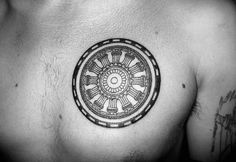 a black and white photo of a man's chest with a circular tattoo on it