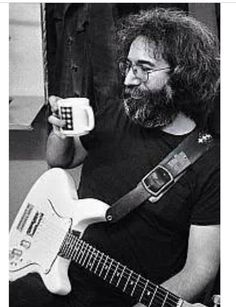 a man sitting in a room holding a white guitar