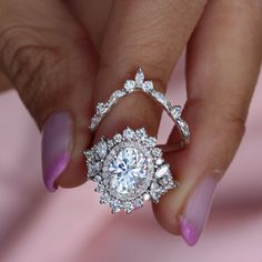 a woman's hand holding an engagement ring with diamonds on the middle and sides