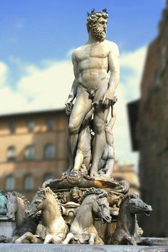 a statue of a man standing on top of a fountain surrounded by horses and lions