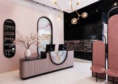 the interior of a nail salon with pink chairs and mirrors on the wall, chandeliers hanging from the ceiling