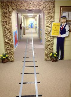 a train track going down the middle of a hallway next to a man in uniform