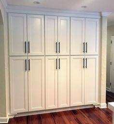 an empty room with white cabinets and wood floors