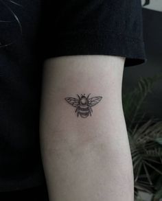 a small black and white bee tattoo on the left arm