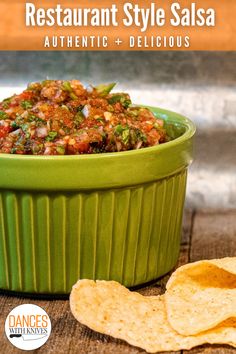 a green bowl filled with salsa next to tortilla chips on top of a wooden table