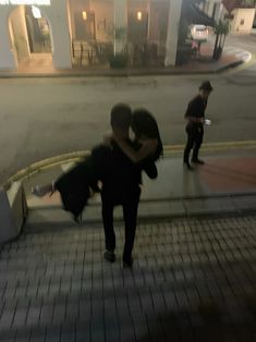 two people hugging each other on the sidewalk