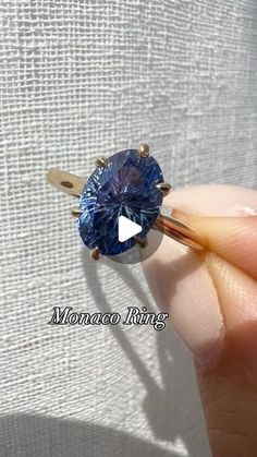 a person holding a ring with a blue diamond in it