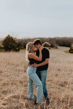 a man and woman hugging in the middle of a field