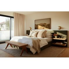 a bedroom with a large bed and wooden flooring next to a sliding glass door