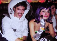 two people dressed up in costumes sitting next to each other on a couch at a party