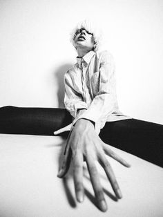 a woman sitting on top of a yoga mat with her hands extended out to the side