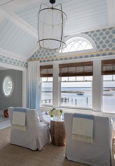 a living room filled with furniture next to a window covered in blue and white curtains