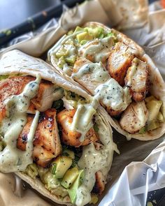 two tacos with chicken, avocado and ranch dressing on them sitting on foil