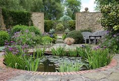 a pond surrounded by plants and flowers in a garden