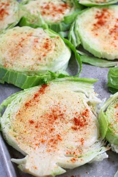 some lettuce leaves with seasoning on them sitting on a baking sheet, ready to be cooked