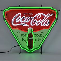 a neon sign that says drink coca - cola on the front and side of it