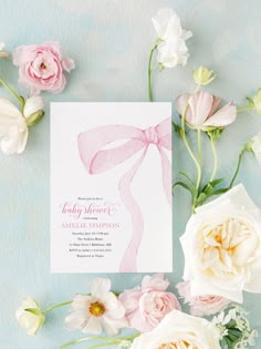 pink and white flowers are next to a baby shower card