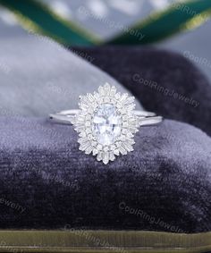 an oval cut diamond ring sits on a velvet cushion