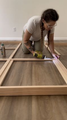 a woman in white shirt and glasses working on wood flooring with glue bottle next to it