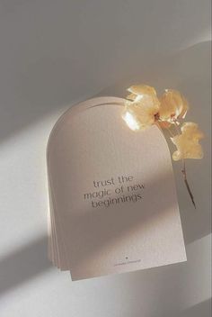 a book with some flowers in it on a white surface and the words trust the magic of new beginnings