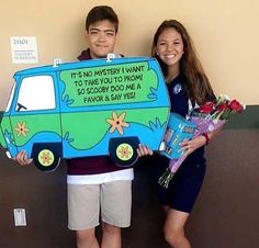 two people standing next to each other holding flowers and a sign that says it's anniversary i want to hug you