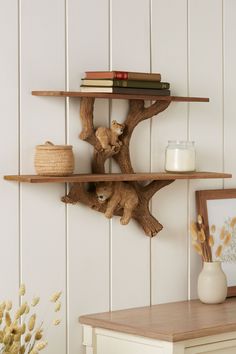 two wooden shelves with books on them in a white room next to a table and vase