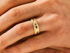 a person's hand with a gold ring on their left and the other hand holding it