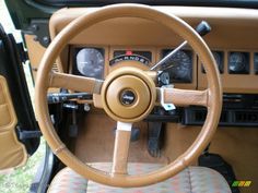 the steering wheel and dashboard of an old car with tan leather upholstered seats