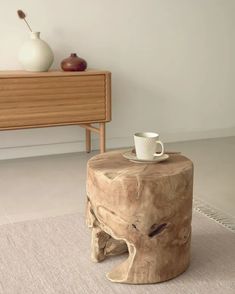 a wooden table with a cup on top of it next to a dresser and vase