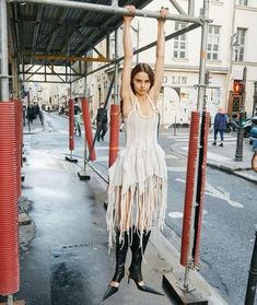 a woman is standing on the street with her arms in the air and wearing fringes