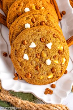 chocolate chip cookies with marshmallows on a white plate next to cinnamon sticks