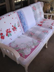 a white couch with red and blue flowers on it's back cushions are sitting in front of a window