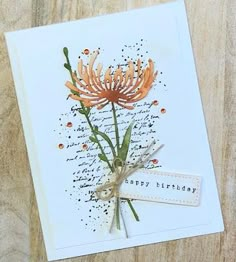 an orange flower is on top of a white card with a tag that says happy birthday