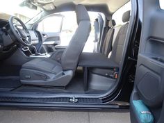 the interior of a vehicle with its door open and seats folded down in front of it