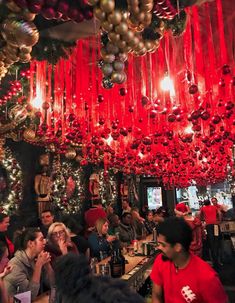 a group of people sitting at a bar with red and gold decorations hanging from the ceiling