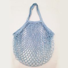 a blue net bag hanging on the wall with a white back ground and light blue handles