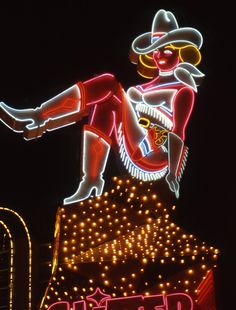 a large neon sign with a cowboy on it's head and arms outstretched in the air