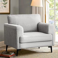 a gray chair sitting on top of a rug next to a window