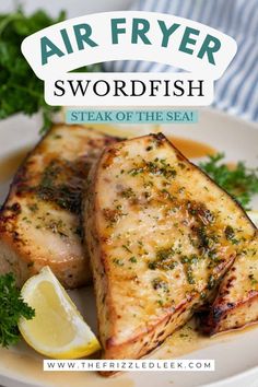 two pieces of fish sitting on top of a white plate with lemon wedges and parsley