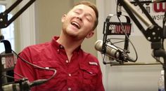 a man in a red shirt singing into a microphone