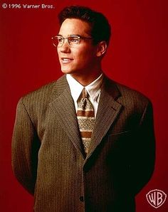 a man in a suit and tie is posing for a photo against a red background