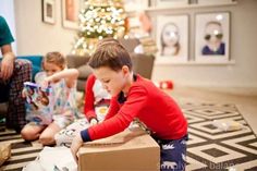 two young boys playing with toys in front of a christmas tree on the living room floor