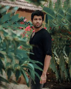 a man is standing in front of some plants and looking at the camera with an intense look on his face