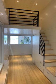 an empty room with wooden floors and stairs leading to the second floor that has been painted white